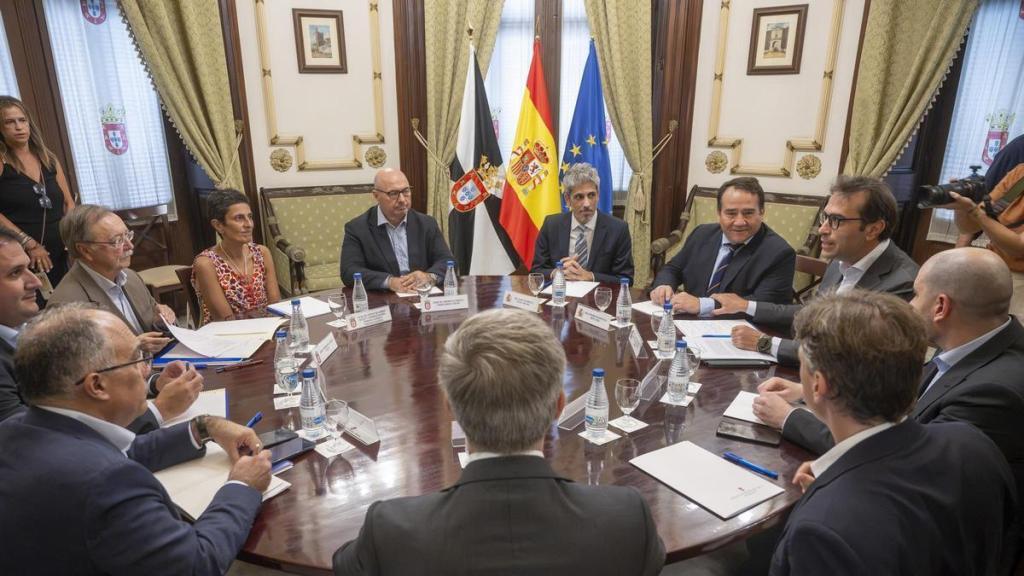 Representantes políticos y autoridades reunidos en una mesa redonda en el Palacio de la Asamblea de Ceuta, con las banderas de España, la Unión Europea y Ceuta de fondo.